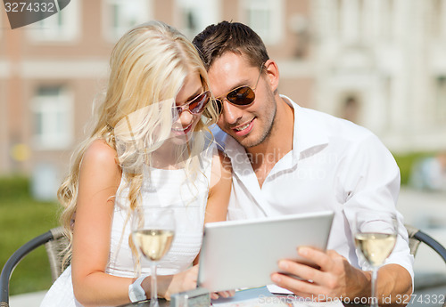 Image of couple looking at tablet pc in cafe