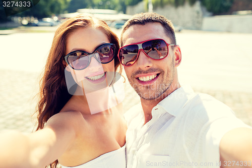 Image of smiling couple wearing sunglasses making selfie