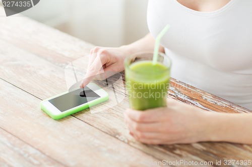 Image of close up of woman with smartphone and green juice