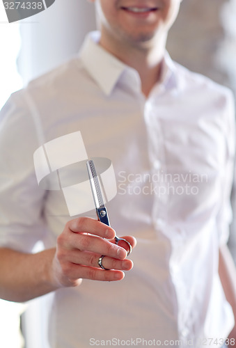 Image of close up of male stylist with scissors at salon