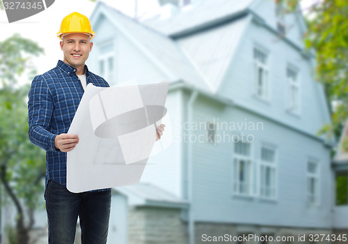 Image of smiling builder with blueprint over house