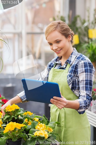 Image of happy woman with tablet pc in greenhouse