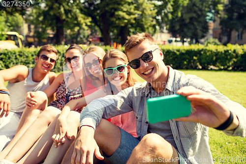 Image of smiling friends with smartphone making selfie