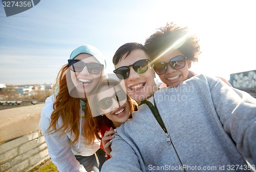 Image of group of happy friends taking selfie on street