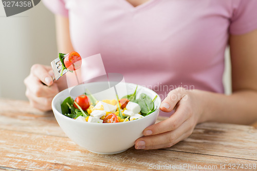 Image of close up of young woman eating salad at home