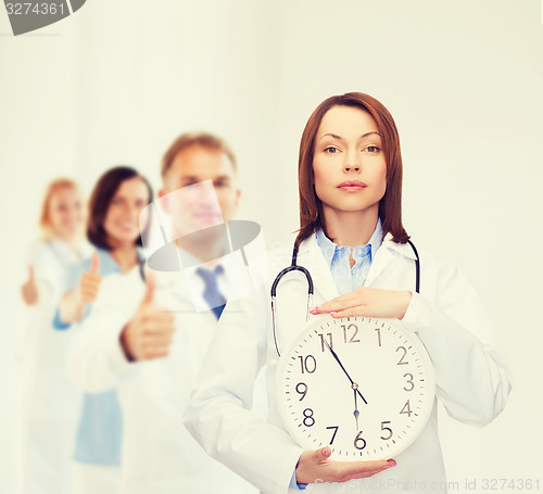 Image of calm female doctor with wall clock