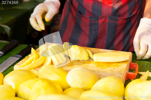 Image of close up of cook hands and mango at street market