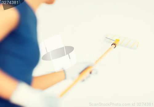 Image of woman with roller and paint colouring the wall