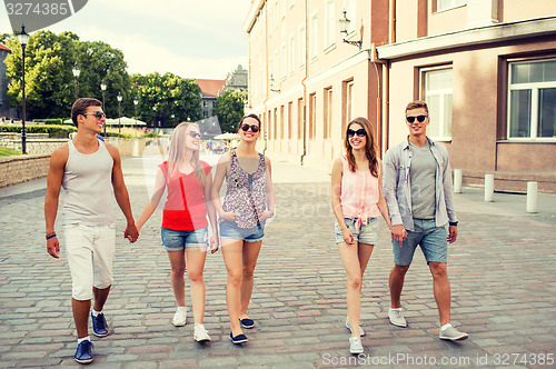 Image of group of smiling friends walking in the city