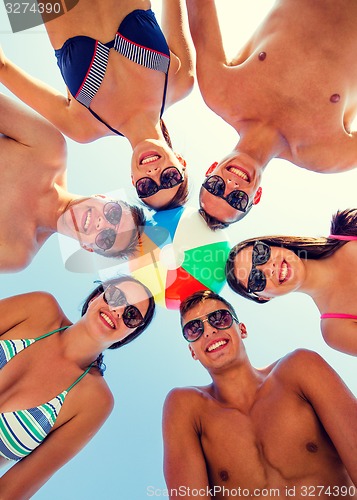 Image of smiling friends in circle on summer beach