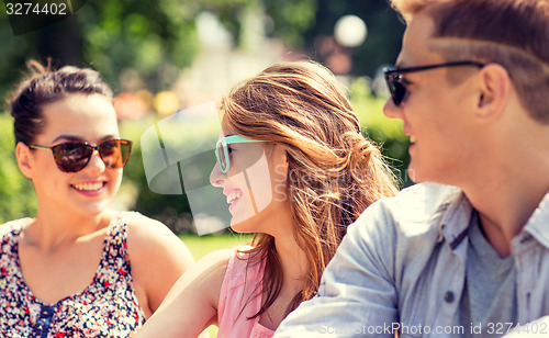 Image of group of smiling friends outdoors sitting in park