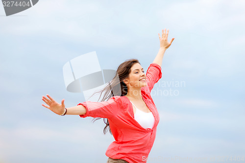 Image of girl with hands up on the beach