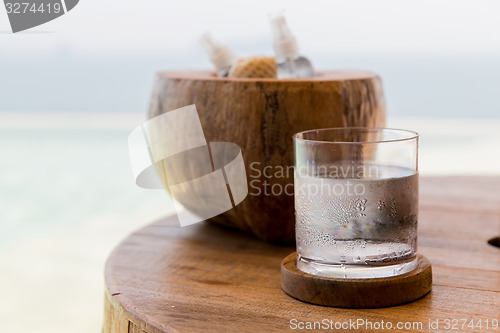 Image of glass of water and moisturizers on table at beach