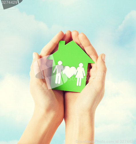 Image of hands holding green house with family