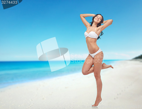 Image of happy young woman in white bikini swimsuit