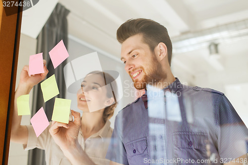 Image of happy creative team writing on stickers at office