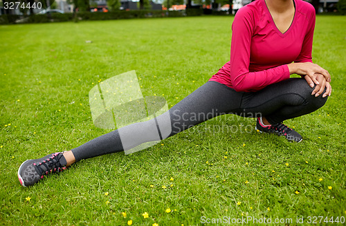 Image of close up of woman stretching leg outdoors