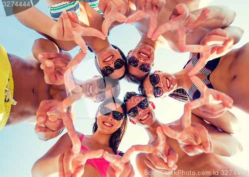 Image of smiling friends in circle on summer beach