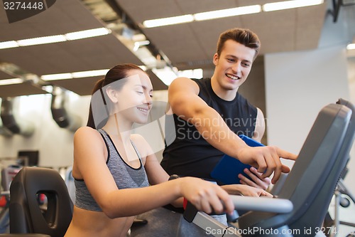 Image of happy woman with trainer on exercise bike in gym