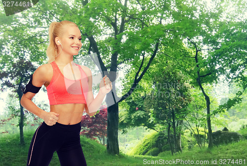 Image of sporty woman running with smartphone and earphones