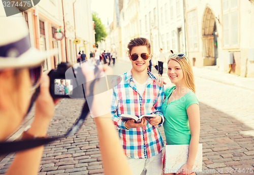 Image of smiling couple with map and photo camera in city