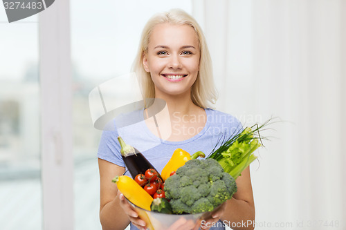 Image of smiling young woman with vegetables at home