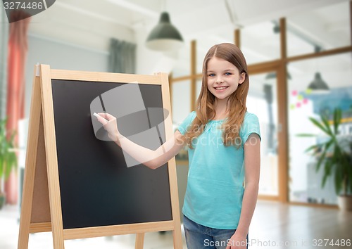 Image of happy little girl with blackboard and chalk