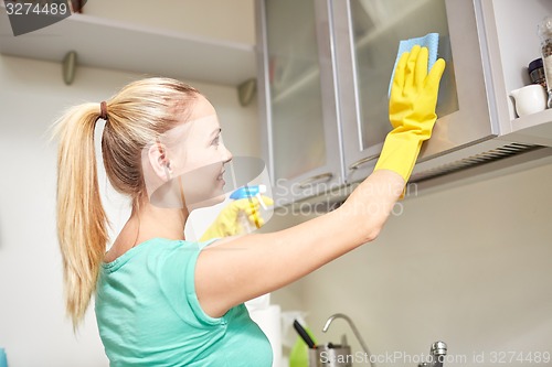 Image of happy woman cleaning cabinet at home kitchen