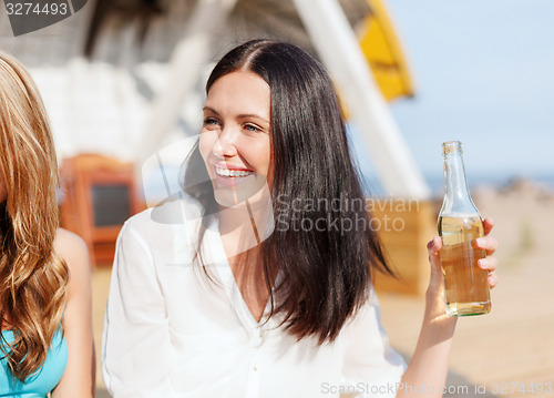 Image of girl with drink and friends on the beach