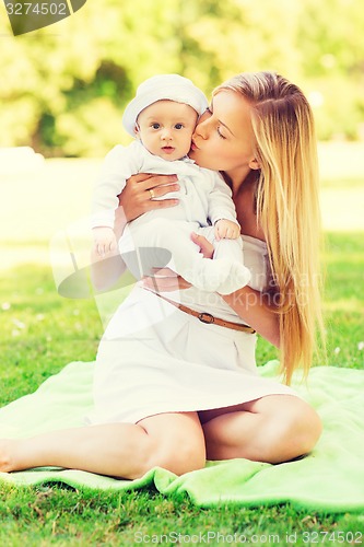 Image of happy mother with little baby sitting on blanket