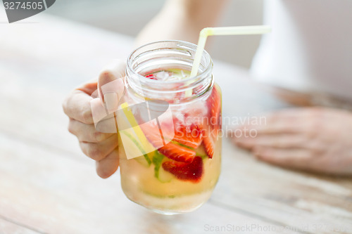 Image of close up of woman holding glass with fruit water