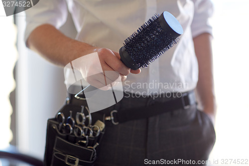Image of close up of male stylist with brush at salon