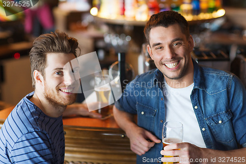 Image of happy male friends drinking beer at bar or pub