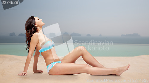 Image of happy woman tanning in bikini over swimming pool