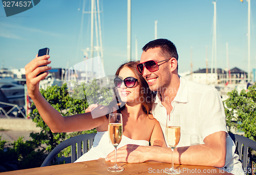 Image of smiling couple drinking champagne at cafe