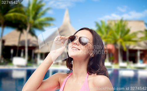Image of happy woman in sunglasses and swimsuit on beach