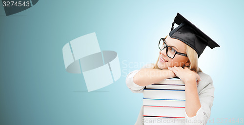 Image of happy student in mortar board cap with books