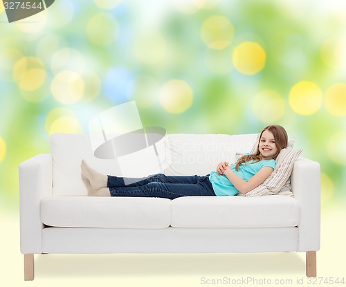 Image of smiling little girl lying on sofa