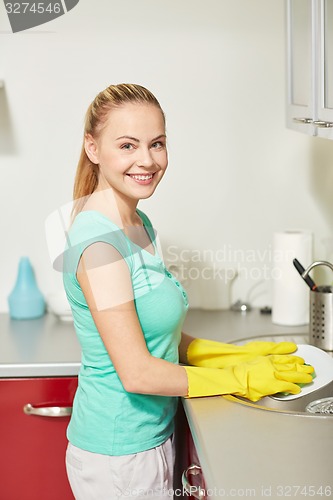 Image of happy woman washing dishes at home kitchen