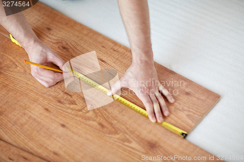 Image of close up of male hands measuring flooring
