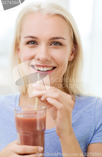 Image of smiling woman drinking juice or shake at home