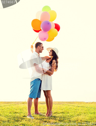 Image of smiling couple with air balloons outdoors