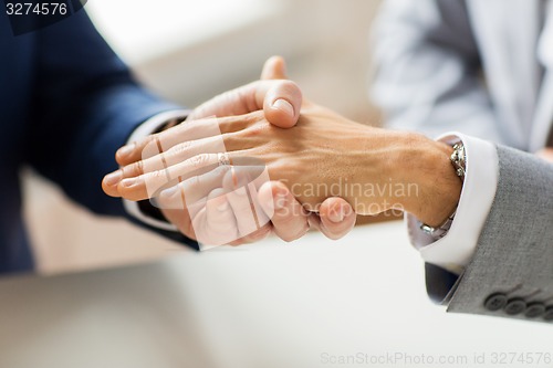 Image of close up of male gay couple hands and wedding ring