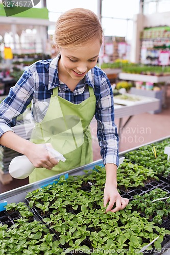 Image of woman with sprayer and seedling in greenhouse