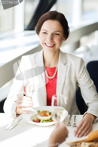 Image of happy woman drinking champagne at restaurant