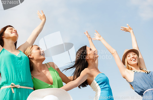 Image of smiling girls with hands up on the beach