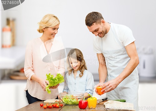 Image of happy family cooking vegetable salad for dinner