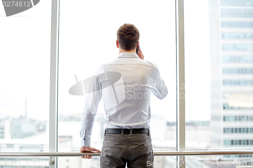 Image of businessman calling on smartphone in office