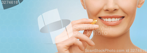 Image of beautiful woman holding omega 3 vitamins capsule