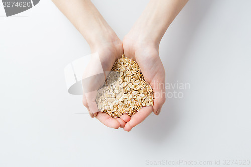 Image of close up of woman hands holding oatmeal flakes